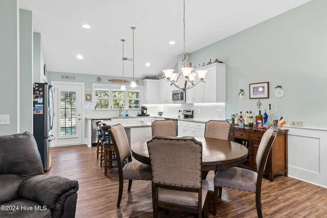 1296 Marsilio Ln SW Unit A, Ocean Isle Beach, NC 28469 - dining area featuring a chandelier, wood finished floors, recessed lighting, a wainscoted wall, and vaulted ceiling
