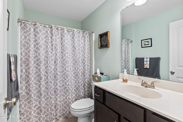 bathroom with toilet, vanity, and curtained shower