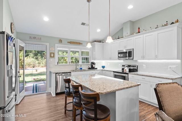 kitchen with stainless steel appliances, hanging light fixtures, sink, white cabinets, and a center island