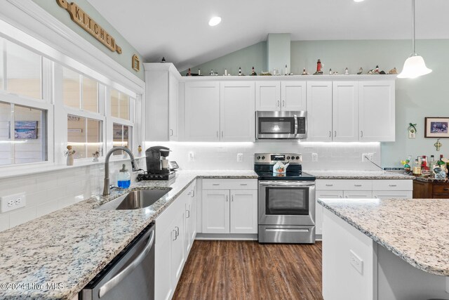 1296 Marsilio Ln SW Unit A, Ocean Isle Beach, NC 28469 - kitchen with stainless steel appliances, a sink, decorative backsplash, white cabinets, and lofted ceiling