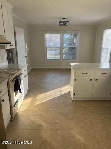 kitchen featuring crown molding, a healthy amount of sunlight, white range, and white cabinets