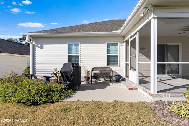 rear view of property with ceiling fan, a sunroom, and a patio