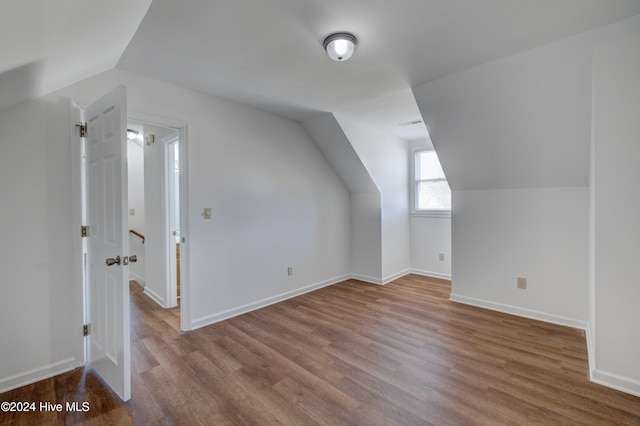 additional living space featuring light hardwood / wood-style floors and vaulted ceiling