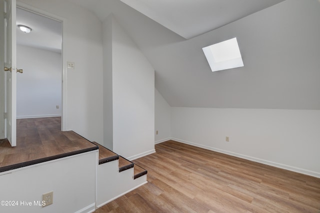 bonus room featuring vaulted ceiling with skylight and light hardwood / wood-style floors