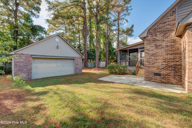 view of yard with a garage, a sunroom, an outdoor structure, and a patio area