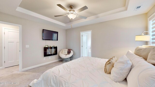 carpeted bedroom with ceiling fan and a raised ceiling