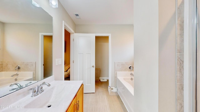 bathroom with tiled bath and vanity