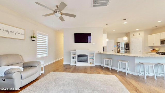 living room with ceiling fan and light hardwood / wood-style flooring