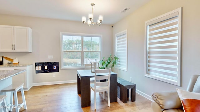 dining space with light hardwood / wood-style floors and a chandelier