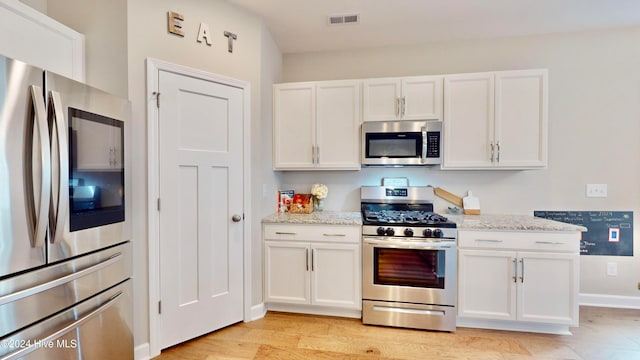 kitchen with white cabinetry, appliances with stainless steel finishes, and light hardwood / wood-style flooring