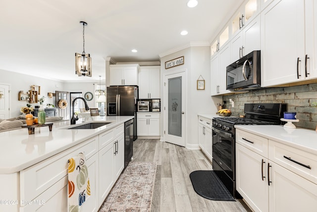 kitchen with black appliances, decorative backsplash, pendant lighting, sink, and white cabinetry