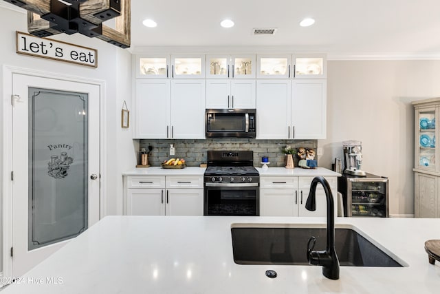 kitchen featuring sink, backsplash, white cabinets, and stainless steel appliances