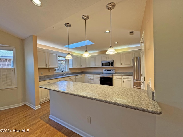 kitchen with plenty of natural light, light wood-type flooring, kitchen peninsula, and stainless steel appliances