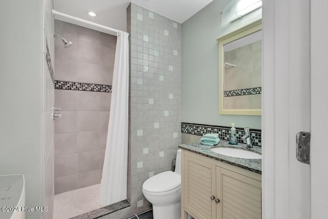 bathroom with curtained shower, vanity, tile walls, and toilet