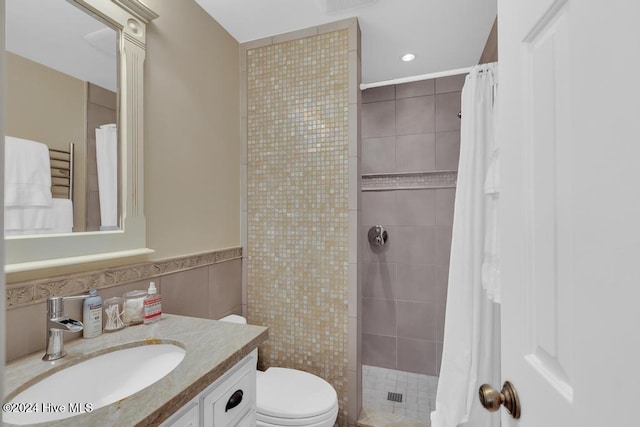 bathroom with a shower with shower curtain, vanity, toilet, and tile walls