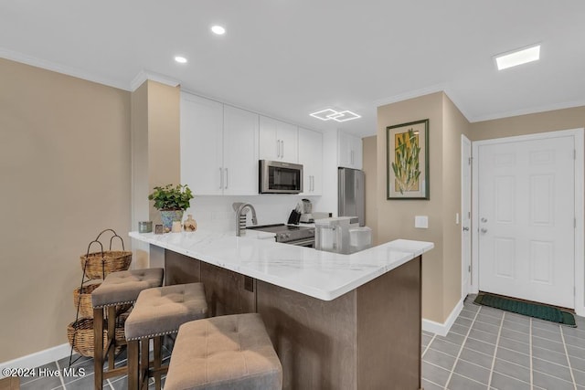 kitchen with kitchen peninsula, stainless steel appliances, white cabinetry, a breakfast bar area, and light tile patterned flooring