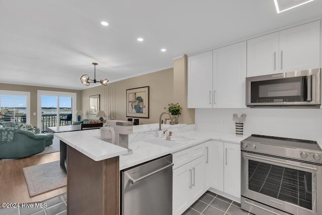 kitchen featuring kitchen peninsula, appliances with stainless steel finishes, a chandelier, and dark hardwood / wood-style floors