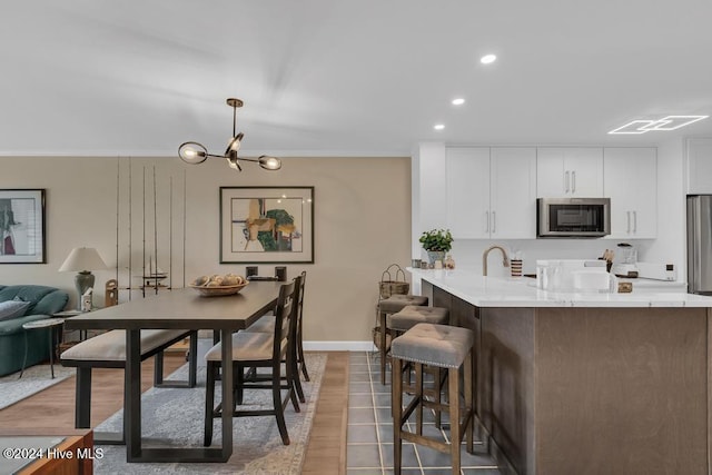 kitchen with an inviting chandelier, light wood-type flooring, appliances with stainless steel finishes, decorative light fixtures, and white cabinetry