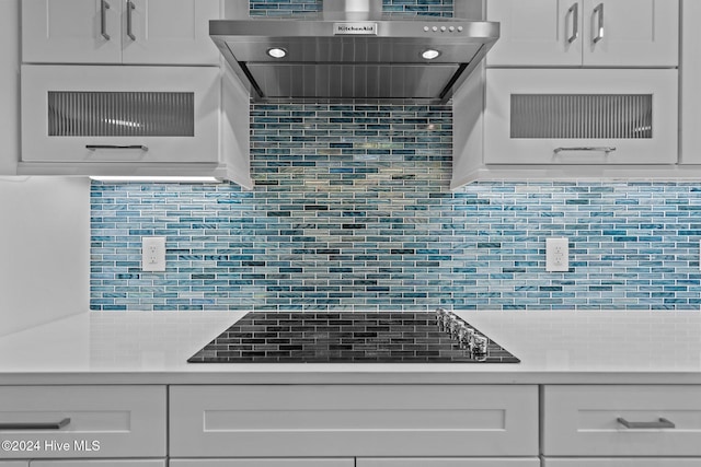 kitchen with white cabinetry, black electric stovetop, decorative backsplash, and wall chimney exhaust hood