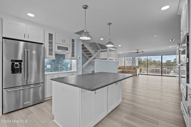 kitchen featuring high quality fridge, white microwave, light wood-style flooring, a kitchen island, and visible vents