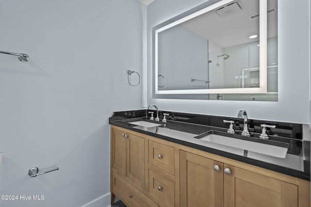 full bathroom with double vanity, a shower, a sink, and visible vents