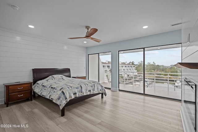 bedroom with access to exterior, wood walls, ceiling fan, and light wood-type flooring