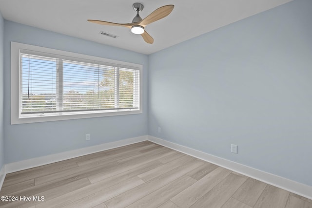 spare room with ceiling fan, light wood finished floors, visible vents, and baseboards