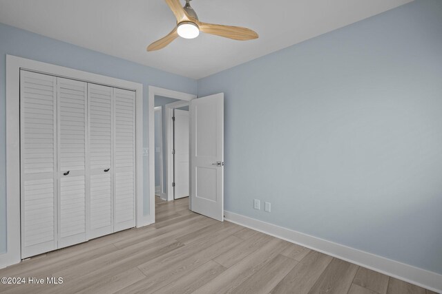 unfurnished bedroom featuring baseboards, a closet, a ceiling fan, and light wood-style floors