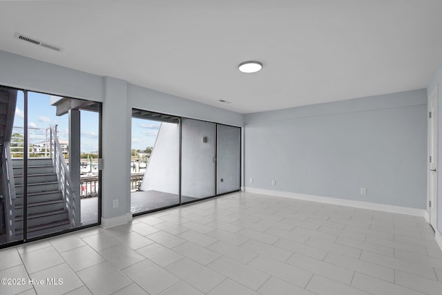 unfurnished room featuring stairs, plenty of natural light, visible vents, and baseboards