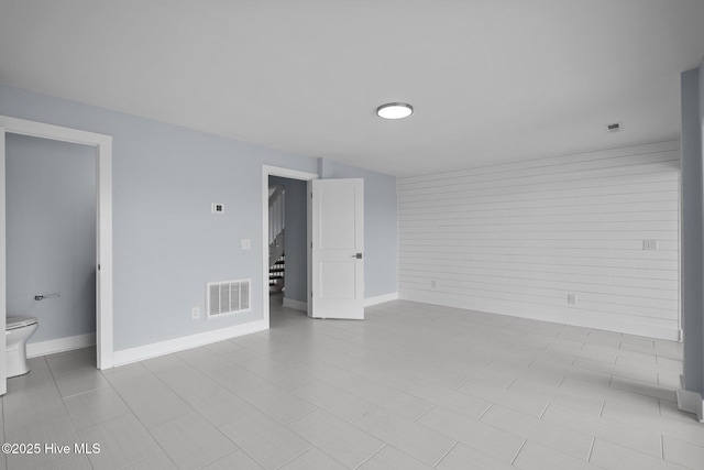 empty room with stairs, visible vents, and baseboards