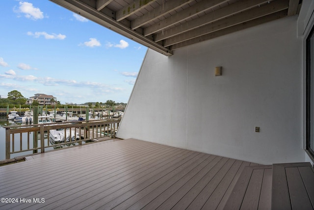 wooden deck with a dock, a water view, and boat lift