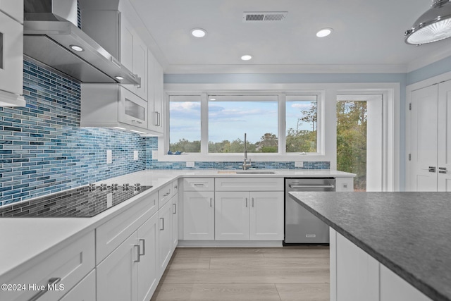 kitchen featuring visible vents, dishwasher, black electric stovetop, wall chimney range hood, and a sink