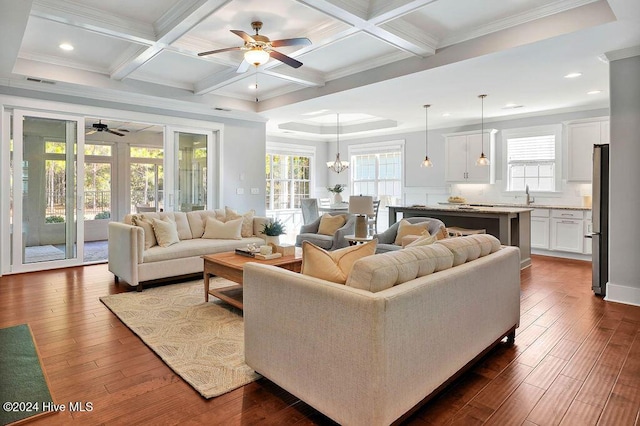 living room featuring coffered ceiling, ceiling fan with notable chandelier, sink, beamed ceiling, and dark hardwood / wood-style flooring