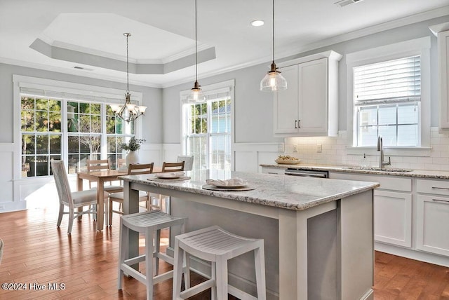 kitchen featuring a breakfast bar, light hardwood / wood-style flooring, white cabinets, and pendant lighting