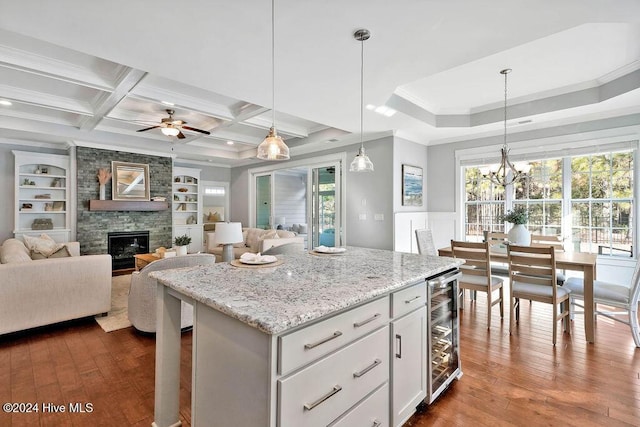 kitchen with a fireplace, beverage cooler, dark wood-type flooring, pendant lighting, and white cabinets