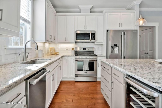 kitchen featuring hanging light fixtures, sink, white cabinetry, stainless steel appliances, and beverage cooler