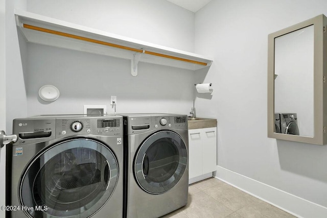 clothes washing area with separate washer and dryer, light tile patterned flooring, and cabinets