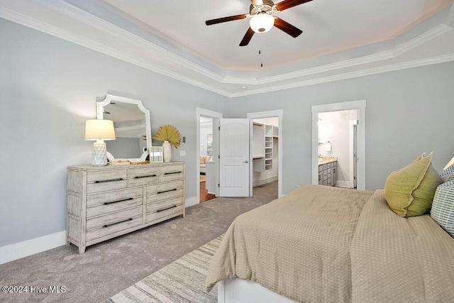 bedroom with connected bathroom, ceiling fan, a tray ceiling, a walk in closet, and a closet