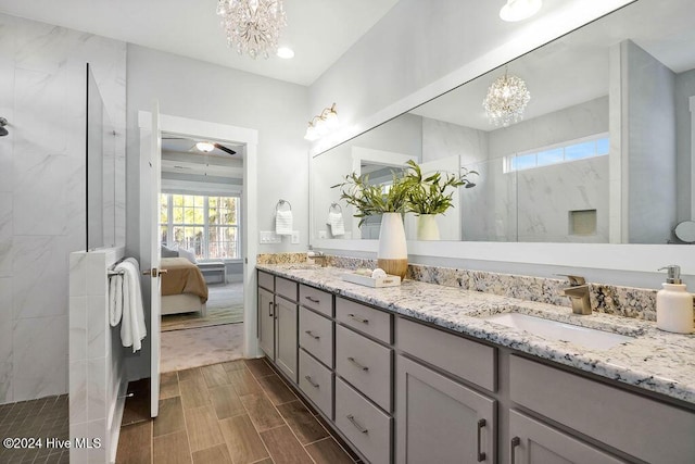 bathroom with a tile shower, vanity, and an inviting chandelier