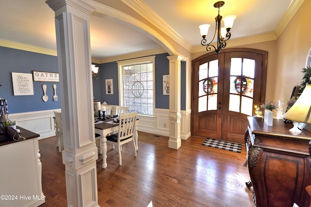 foyer entrance with french doors, ornate columns, crown molding, an inviting chandelier, and dark hardwood / wood-style floors