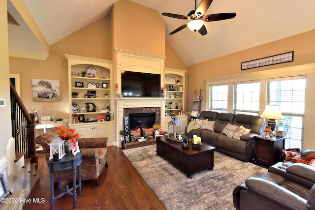 living room with built in features, high vaulted ceiling, dark hardwood / wood-style flooring, ceiling fan, and a brick fireplace