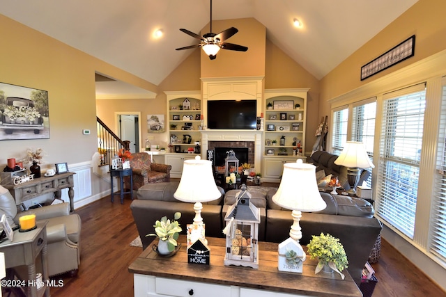 living room featuring dark wood-type flooring, a large fireplace, ceiling fan, and high vaulted ceiling