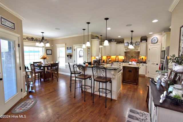 kitchen featuring ornamental molding, a breakfast bar area, and decorative light fixtures