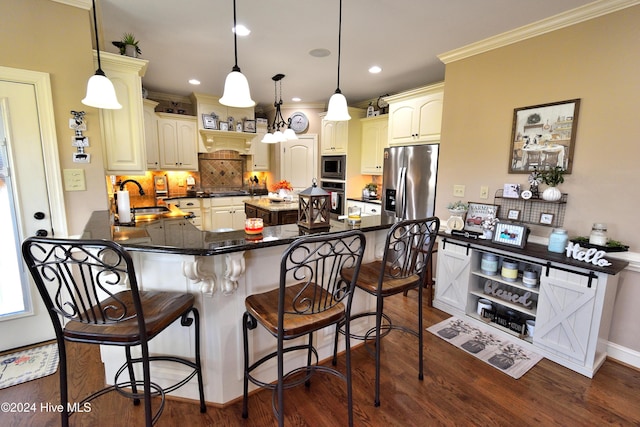 kitchen with hanging light fixtures, a breakfast bar area, sink, and appliances with stainless steel finishes