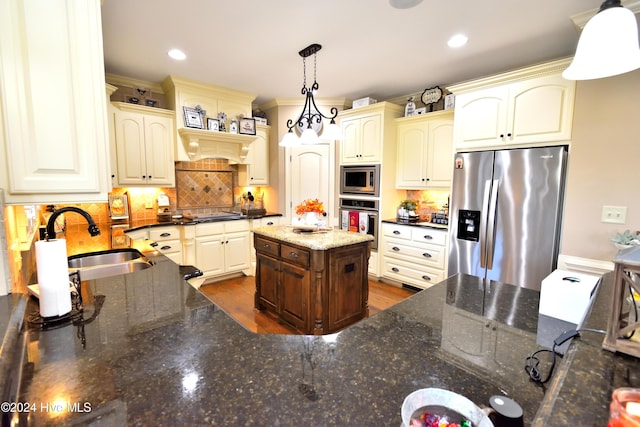 kitchen with sink, dark stone countertops, appliances with stainless steel finishes, pendant lighting, and decorative backsplash