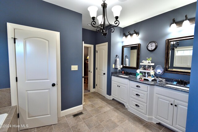 bathroom with vanity, a notable chandelier, and tiled tub