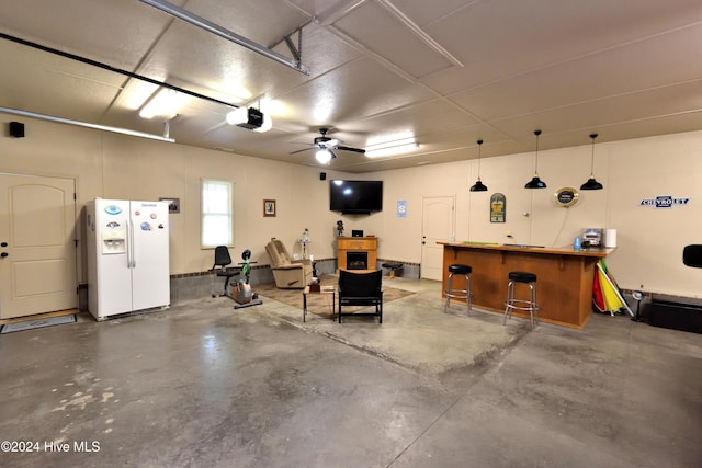 garage with a garage door opener and white refrigerator with ice dispenser