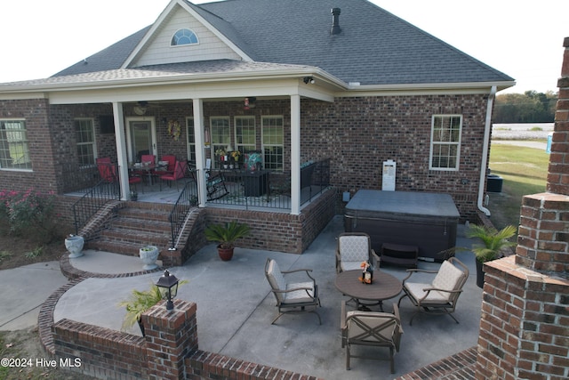 back of property featuring a hot tub and a patio