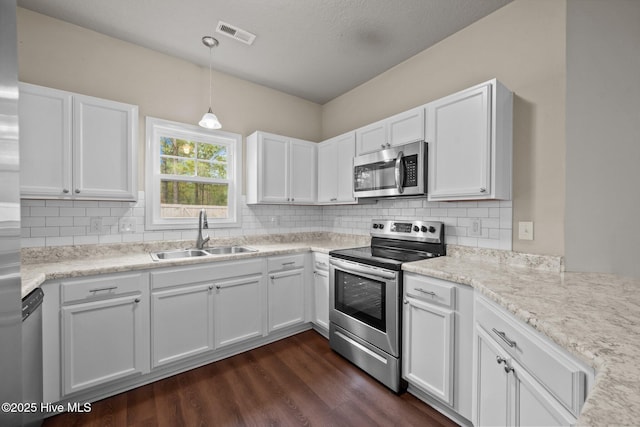 kitchen featuring hanging light fixtures, sink, decorative backsplash, appliances with stainless steel finishes, and white cabinetry