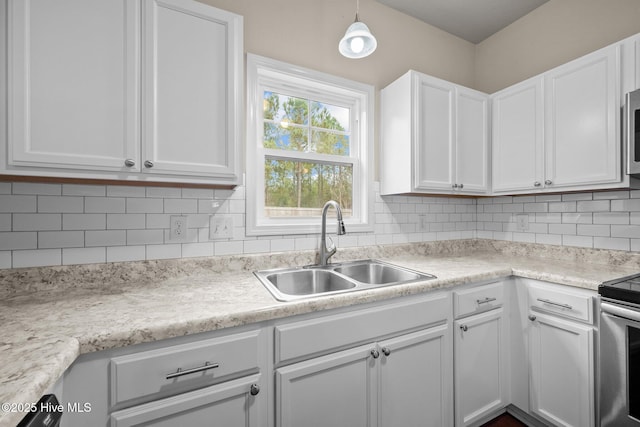 kitchen with backsplash, white cabinets, sink, hanging light fixtures, and stainless steel appliances